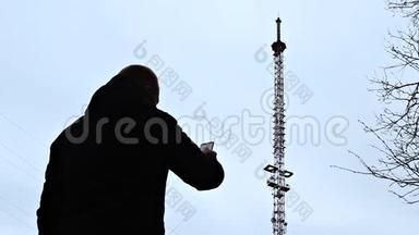 一个拿着电话的人正站在电话塔旁，拨通电话号码，试图接通网络，这是个坏消息